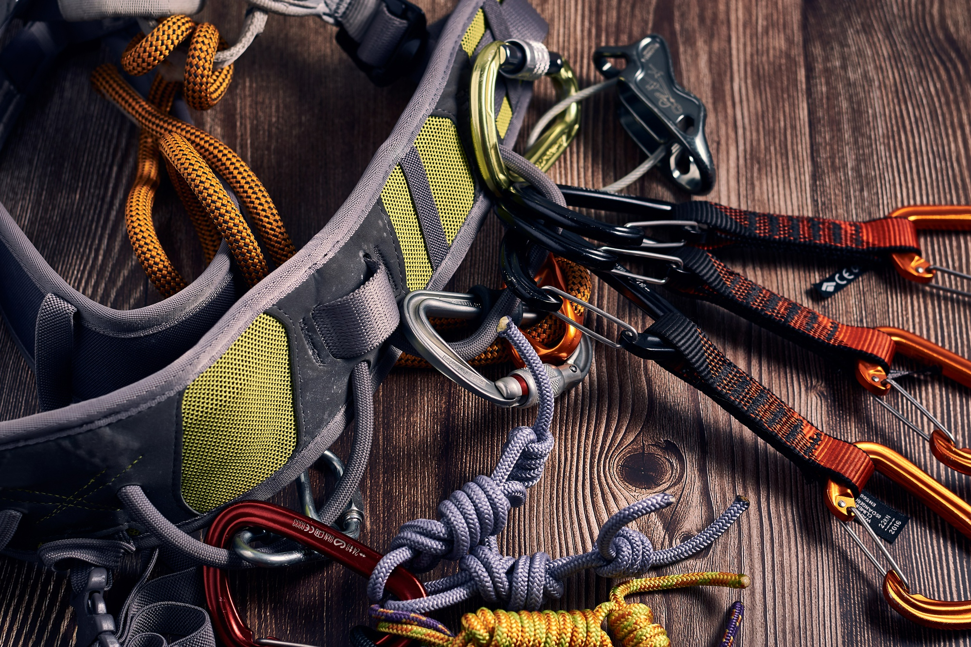closeup shot many colorful climbing carabiners knots wooden surface